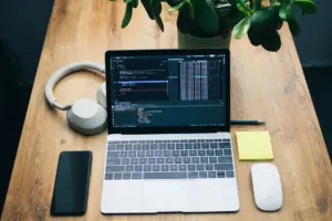 A desk with a laptop, headphones and small gadgets arranged around it